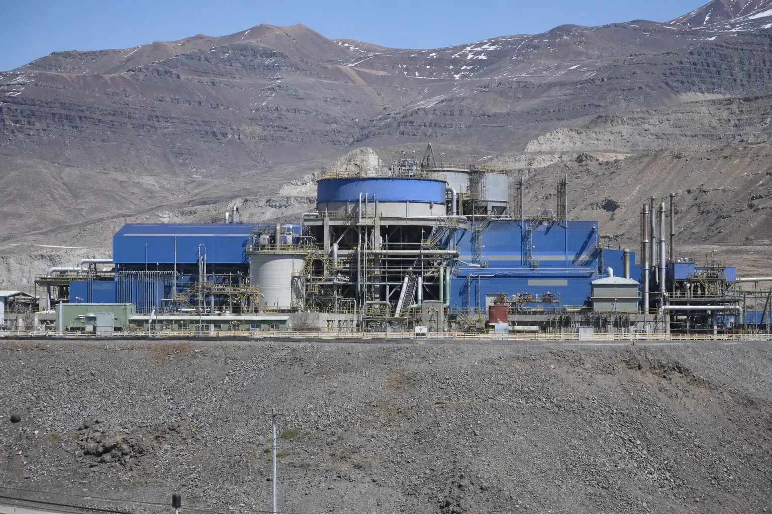 The surface facilities and processing plant of Codelco's El Teniente underground copper mine set against the surrounding Andean mountainside under flat daylight
