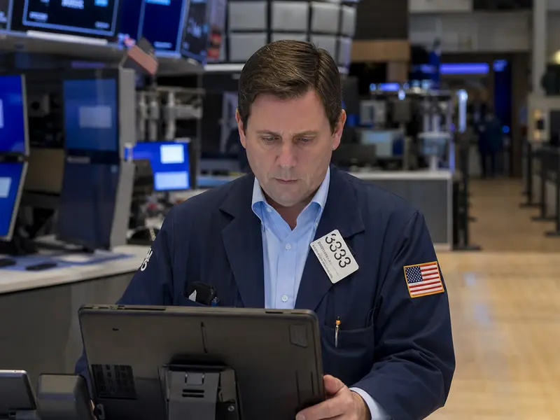 A trading floor at the New York Stock Exchange seen straight-on in ordinary daylight, with traders at their terminals during a working session.