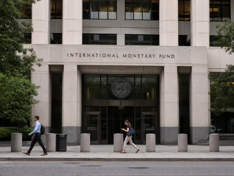 A straight front-on daylight view of the International Monetary Fund headquarters building in Washington, DC, its name lettering visible on the stone facade abo