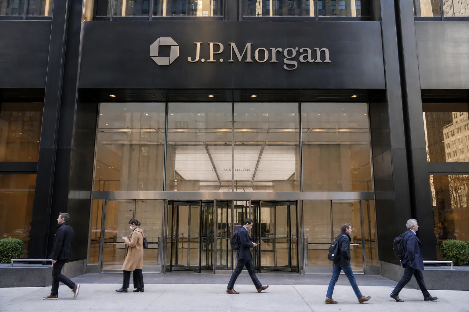 A straight front-on daylight view of the J.P. Morgan office tower entrance in Manhattan, with the firm's octagon logo and wordmark visible incidentally on the b