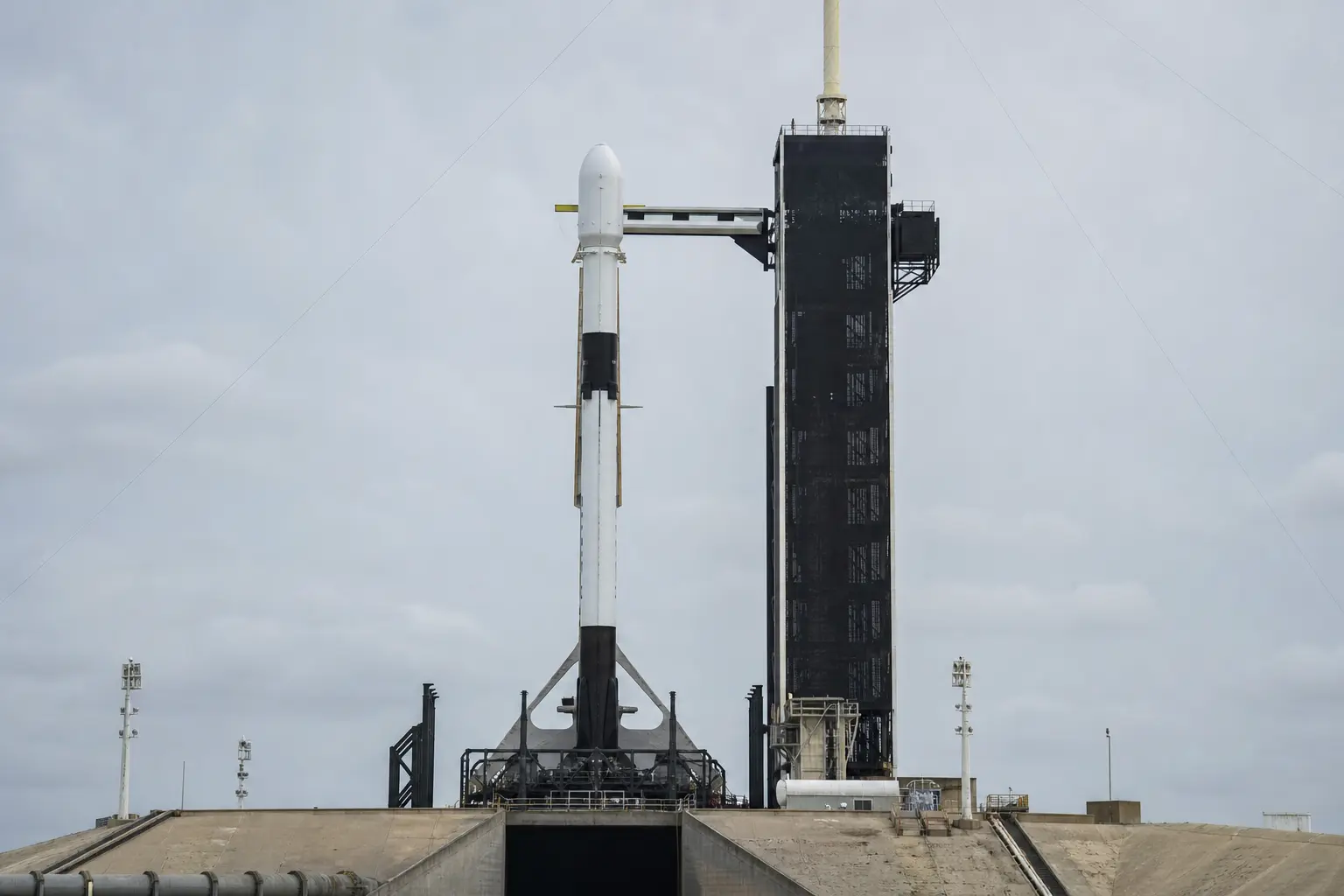 A SpaceX Falcon 9 rocket standing upright on its launch pad photographed head-on in flat daylight.