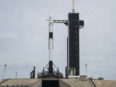 A SpaceX Falcon 9 rocket standing upright on its launch pad photographed head-on in flat daylight.