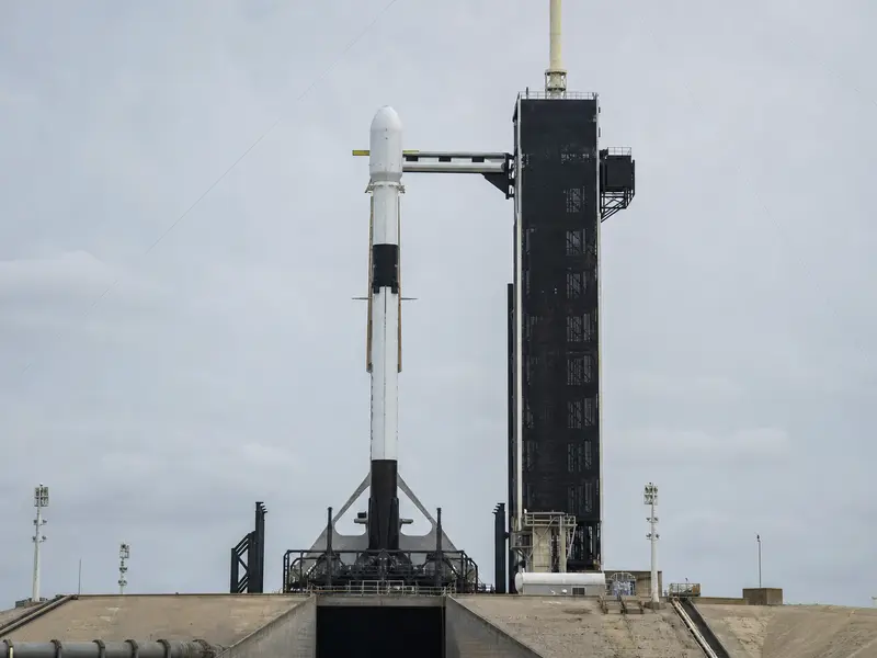 A SpaceX Falcon 9 rocket standing upright on its launch pad photographed head-on in flat daylight.